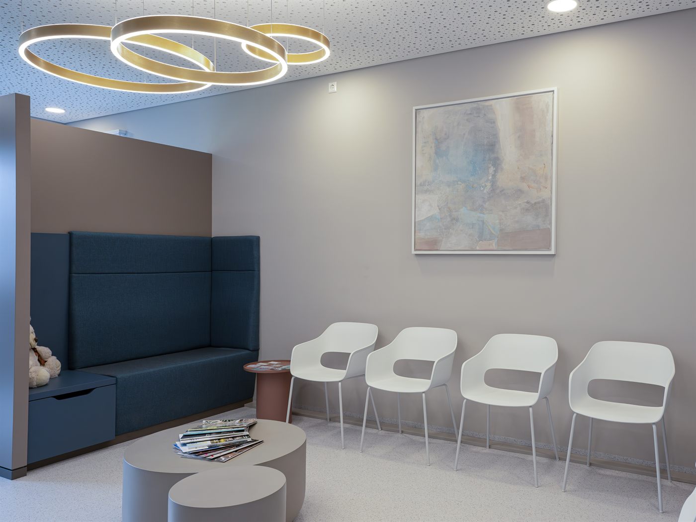 Wartebereich mit heller Sitzgruppe und goldenen Ringleuchten